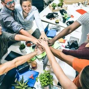 Young employee startup workers group stacking hands at urban studio